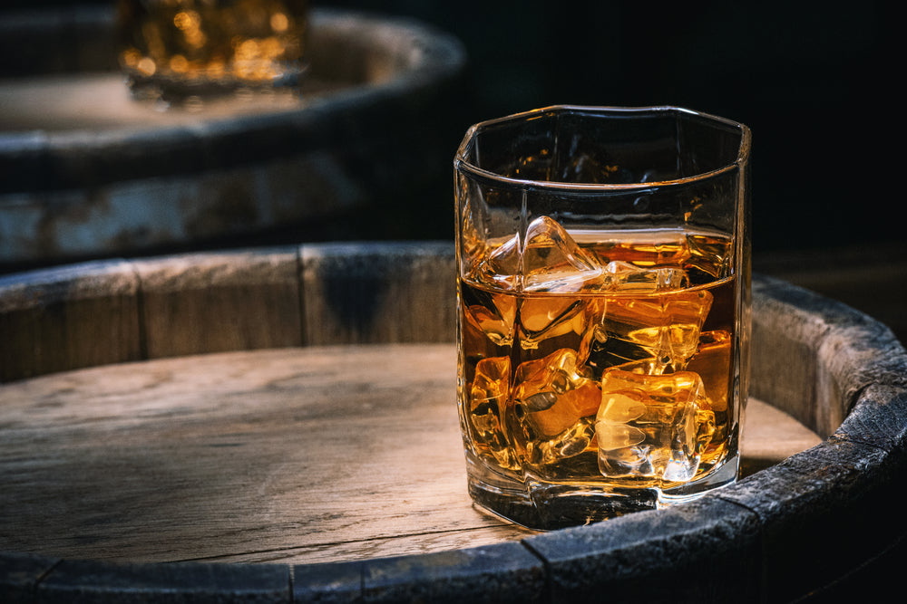 bicchiere di whiskey sopra una botte
